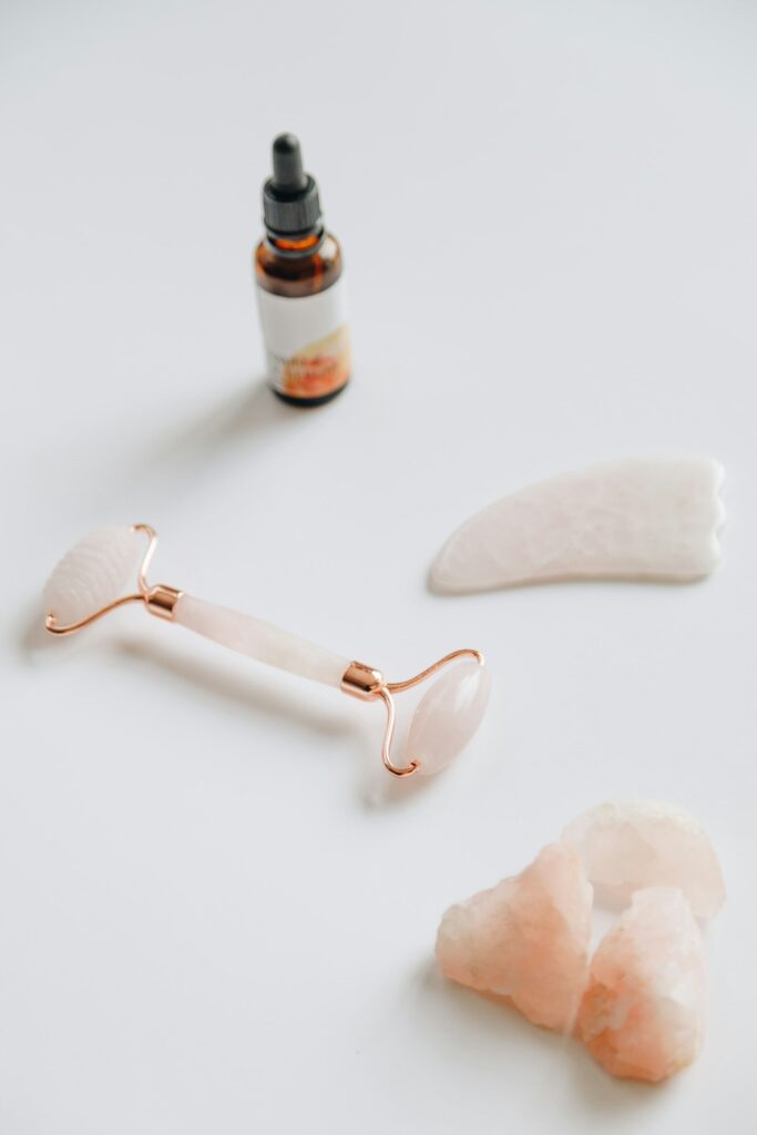 Rose quartz face roller and gua sha set on a clean wellness flat lay