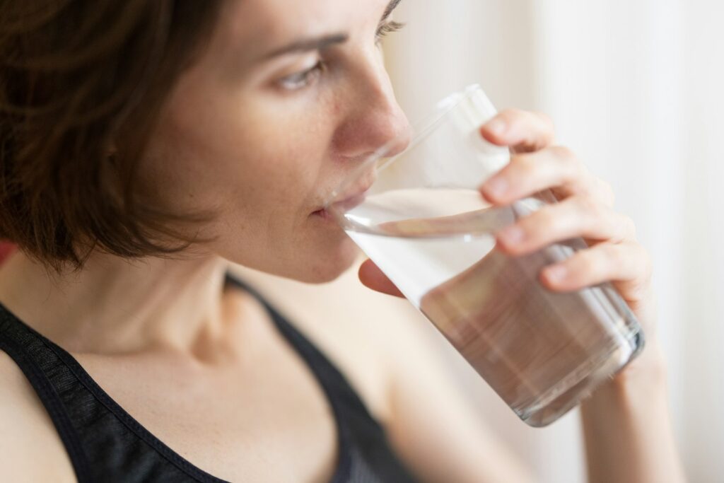 Woman in black tank top drinking a glass of fresh water