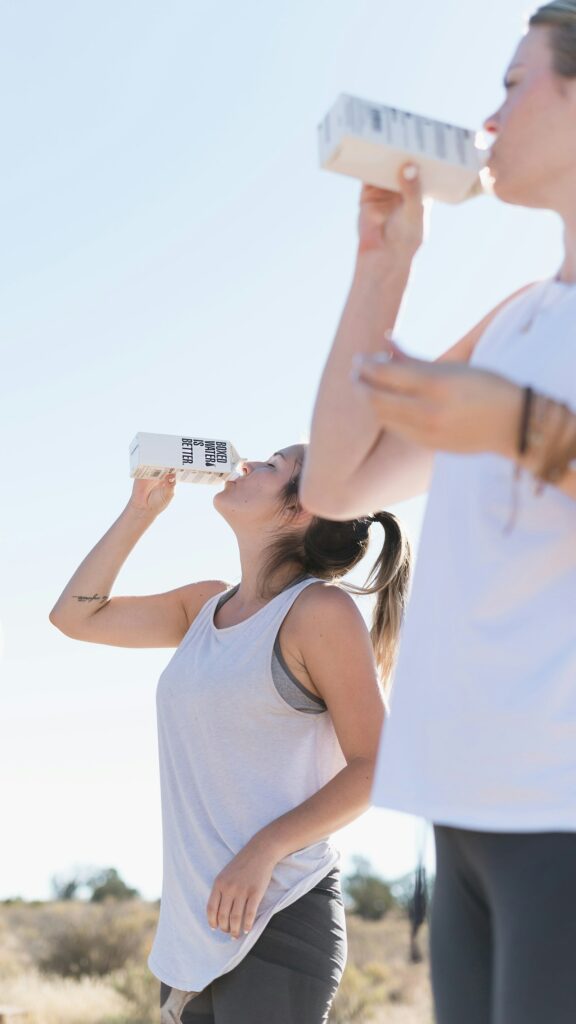 Two women drinking water after a workout, evoking wellness and hydration